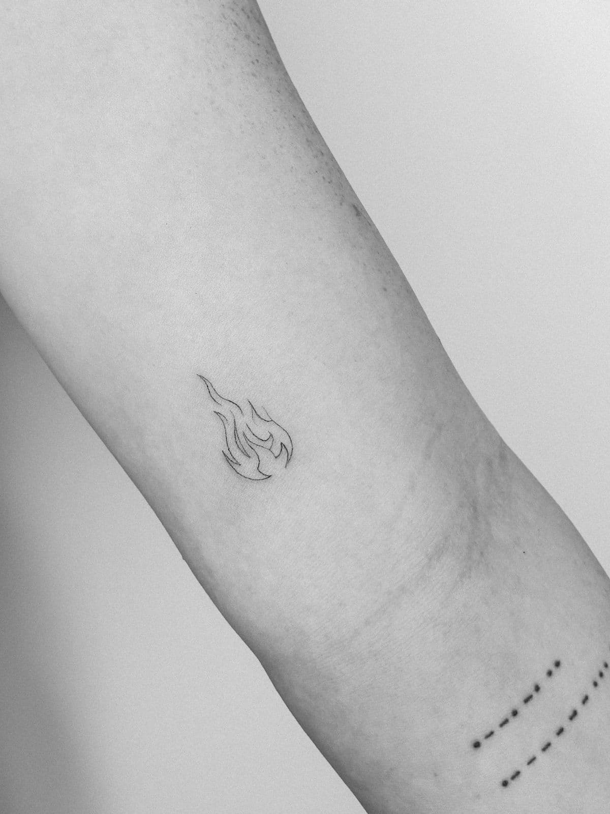 Kleine Flamme und Punktreihe am Handgelenk