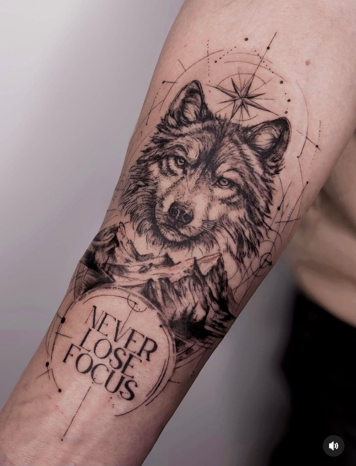Wolf mit Schriftzug ‚Never lose focus‘ am Unterarm