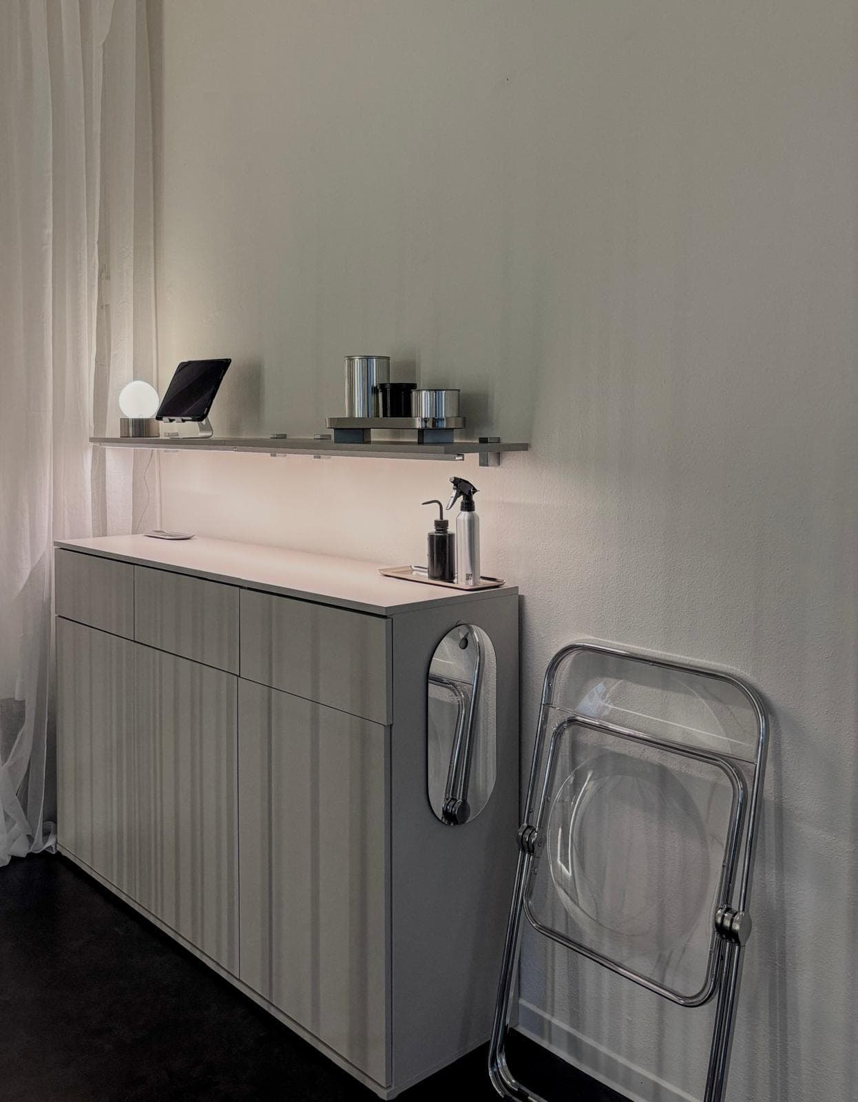 Sideboard mit Tablet, Sprühflaschen und indirektem Licht